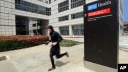 A runner passes the Ronald Reagan UCLA Medical Center on the campus of the University of California, Los Angeles Friday, April 26, 2019. Some students and employees possibly exposed to measles at two Los Angeles universities were still quarantined on campus or told to stay home F