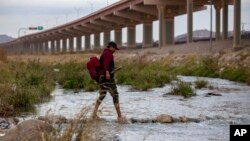 A migrant from Ecuador crosses the Rio Grande toward El Paso, Texas, from Ciudad Juarez, Mexico, Dec. 18, 2022.