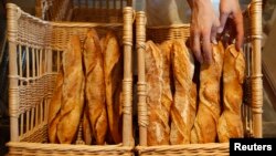 FILE - A French baker places freshly-baked baguettes, the traditional French bread, in wicker baskets in his shop in Strasbourg, eastern France, Aug. 6, 2010. 