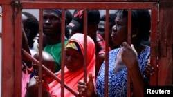 Women look through a gate while waiting to receive food support following a 14-day lockdown aimed at limiting the spread of coronavirus disease (COVID-19), in Abuja, Nigeria April 3, 2020. REUTERS/Afollabi Sotunde
