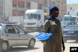 FILE - A vendor sells plastic sachets filled with drinkable water in Dakar, on August 23, 2023.