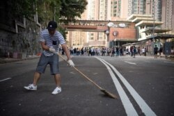 A man sweeps the street as people clear makeshift barricades erected by protesters, outside the University of Hong Kong, in Hong Kong, China, Nov. 16, 2019.