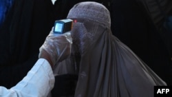 Photo d'illustration d'une femme portant la burqa. Sa température est vérifiée dans le cadre de la lutte anti-Covid (AFP/Arif Ali/19 mars 2020)