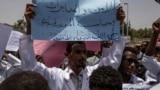 A man holds a banner calling for people who killed protesters to be punished, during a march by members of the Sudanese medical profession syndicate, at the sit-in inside the Armed Forces Square, in Khartoum, April 17, 2019. 