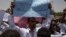A man holds a banner calling for people who killed protesters to be punished, during a march by members of the Sudanese medical profession syndicate, at the sit-in inside the Armed Forces Square, in Khartoum, April 17, 2019. 