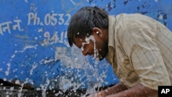 FILE - An Indian worker splashes water on his face as he tries to cool himself on a hot summer day in Allahabad, India.