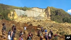 En esta fotografía proporcionada por el PNUD Papúa Nueva Guinea, los aldeanos buscan entre un deslizamiento de tierra en la aldea de Yambali en las Tierras Altas de Papúa Nueva Guinea, el domingo 26 de mayo de 2024.