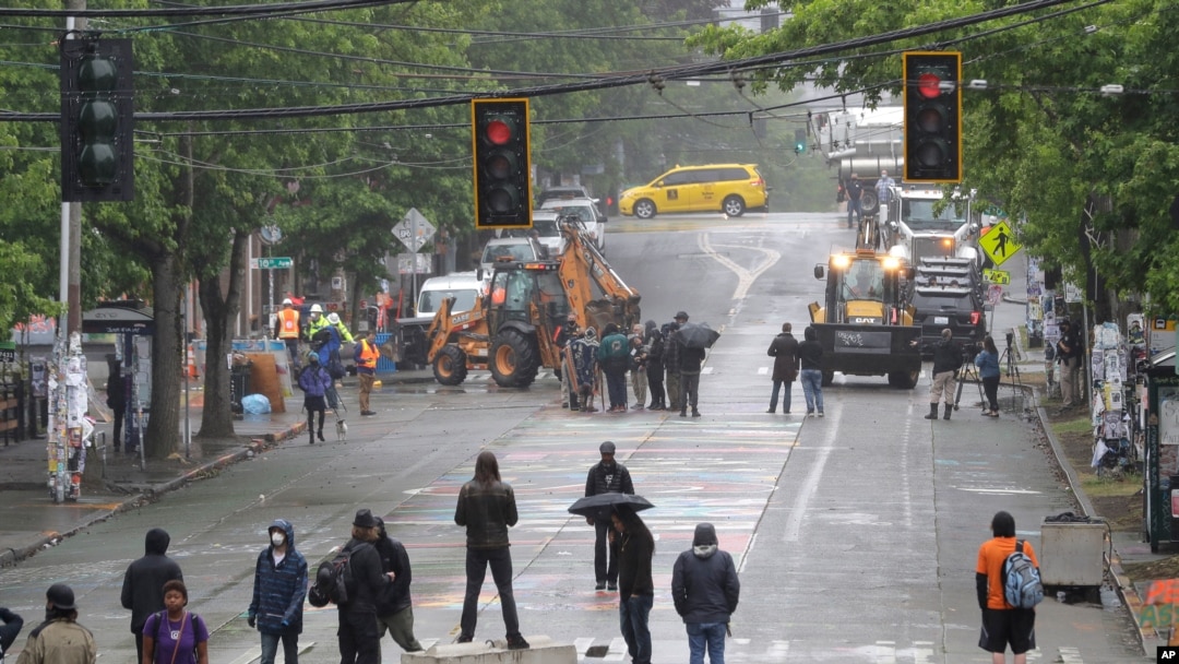 Manifestantes forman barricadas mientras personal del Departamento de Transporte de Seattle remueven otras barricadas en la 10th Ave. y Pine St., en Seattle, Washington, el 30 de junio de 2020.