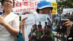 Seorang pembelot Korea Utara membawa foto 9 pembelot Korea Utara untuk memrotes deportasi para pembelot oleh pemerintah Laos (5/6). 