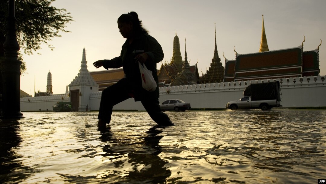 Seorang perempuan berjalan mengarungi banjir, yang diakibatkan musim monsun, di depan Istana Agung dekat Sungai Chao Praya, 28 Oktober 2011.