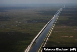 Sections of the Tamiami Trail which have been replaced with bridges to allow water to flow freely into Everglades National Park, at left, are seen from the air in southern Florida, Friday, May 17, 2024.