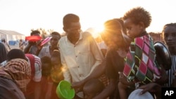 Des réfugiés du Tigré qui ont fui le conflit dans la région du Tigré en Éthiopie, attendent de recevoir du riz cuit servi par des volontaires locaux soudanais au camp de réfugiés d'Um Rakuba à Qadarif, dans l'est du Soudan, le 23 novembre 2020.
