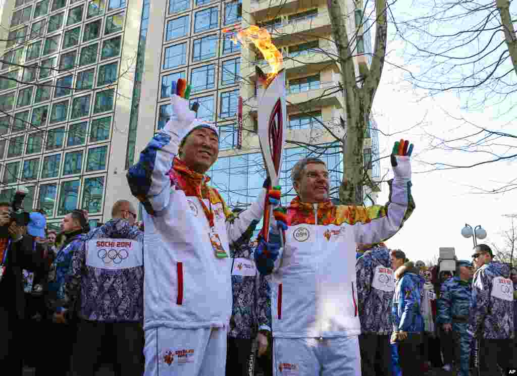 Presiden Komite Olimpiade Internasional Thomas Bach (kanan) memberikan obor Olimpiade pada Sekretaris Jenderal PBB Ban Ki-moon di SOchi (6/2). (AP/Shamil Zhumatov)