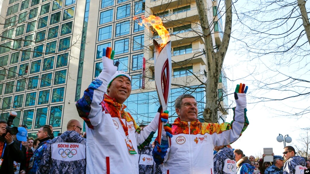 Predsednik MOK-a Tomas Bah predaje Olimpijsku baklju generalnom sekretaru UN Ban Ki-munu pri dolasku štafete u Soči, 6. februara 2014.