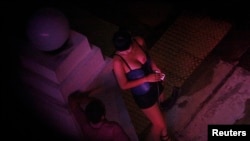 FILE - A sex worker talks to a man outside a hotel in the Geylang red light district in Singapore.