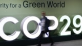 Peserta konferensi terlihat berjalan melewati logo COP29 dalam Konferensi Perubahan Iklim PBB yang berlangsung di Baku, Azerbaijan, pada 21 November 2024. (Foto: AFP)