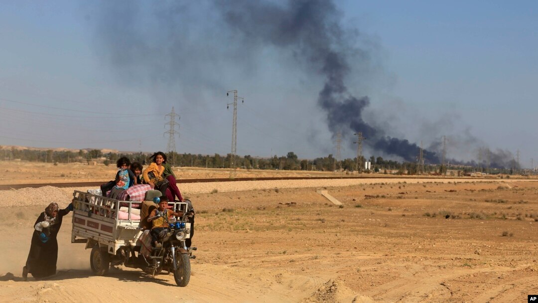 Asap membubung dari pertempuran antara pasukan keamanan Irak dan ISIS, sementara warga mengungsi di Hit, Irak, April 2016. (AP/Khalid Mohammed)