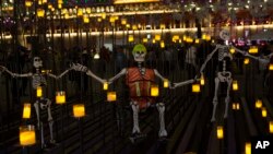 En México, esqueletos de papier-mache representan a rescatistas y voluntarios que trabajaron luego del terremoto del pasado septiembre, se muestran en un altar en honor de las víctimas del sismo durante las festividades en el Zócalo, la plaza principal de la capital mexicana. Oct. 30, 2017.