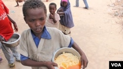 Boy with pot of gruel camp at Badbaado IDP camp in Mogadishu, Somalia. (VOA - P. Heinlein)