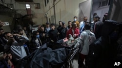 Palestinians carry the body of a person following an Israeli airstrike, into the Al Aqsa hospital in Deir al Balah, Gaza Strip, April 1, 2024. Gaza medical officials say an apparent Israeli airstrike killed four international aid workers with the World Central Kitchen charity.