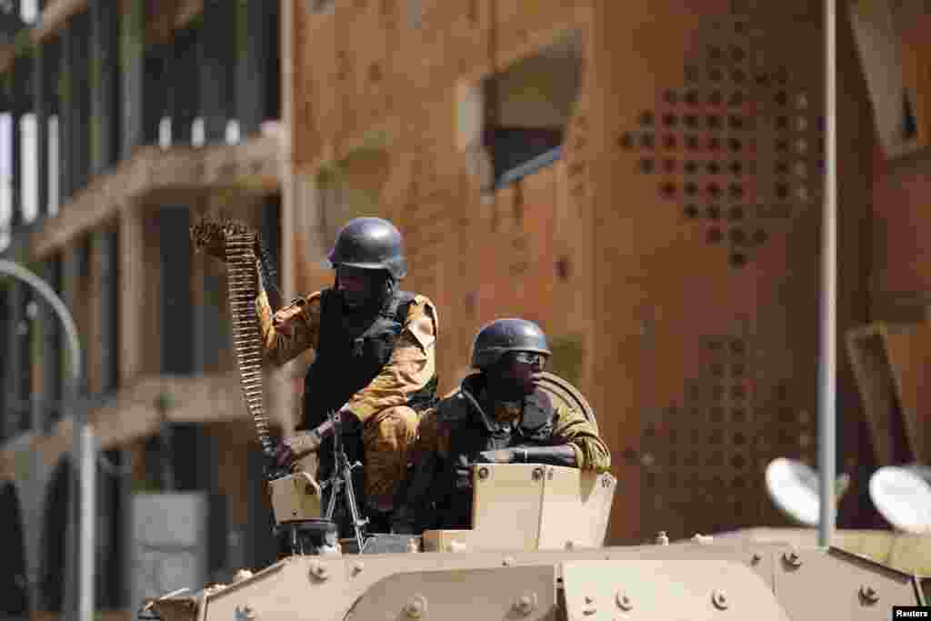 Soldiers stand guard in an armored vehicle outside the Splendid Hotel after al-Qaida militants killed at least 28 people in an attack on the hotel and a restaurant in Ouagadougou, Burkina Faso.