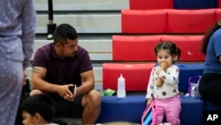 Seorang pria duduk bersama keluarganya di tempat penampungan di Fairview Middle School sebelum Badai Helene melana di Leon County, Florida, 26 September 2024. (Foto: Gerald Herbert/AP Photo)