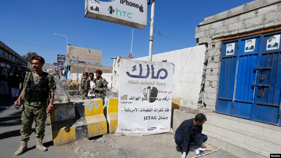 A Houthi militiaman stands guard as a forensic expert inspects the scene of a blast near the republican palace in Sana'a, Feb. 7, 2015.