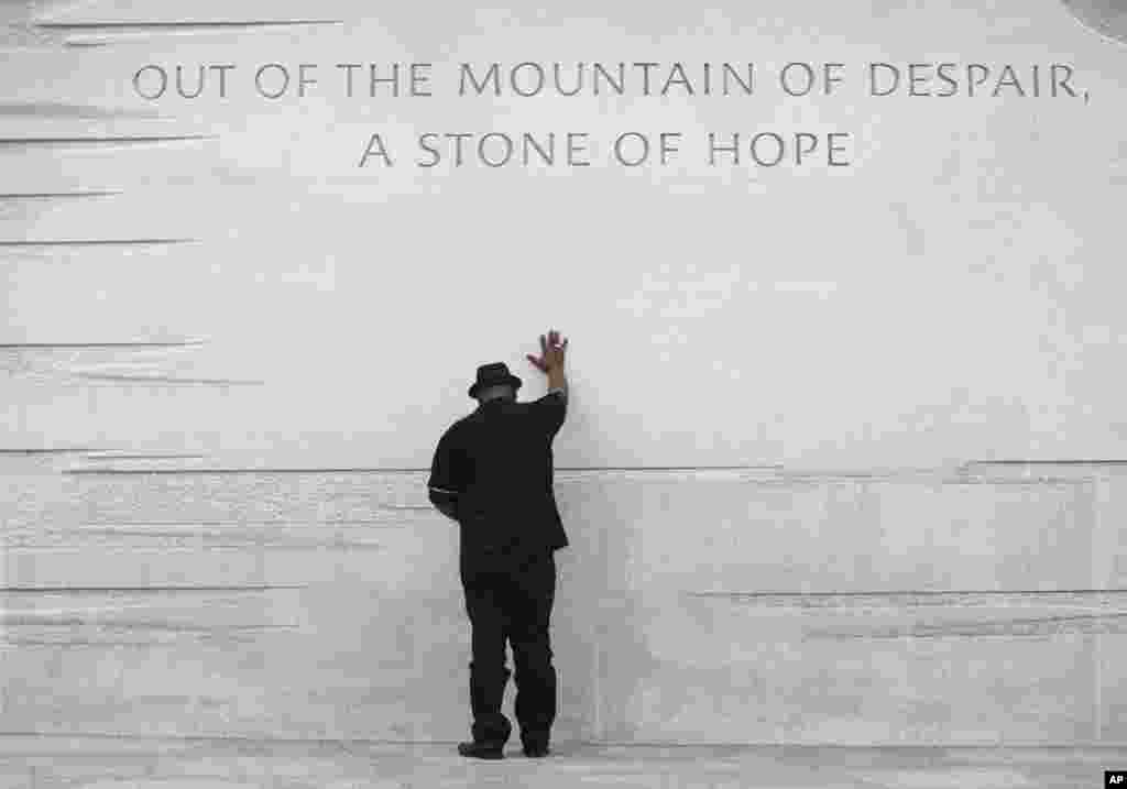 Pendeta Bobby Turner meletakkan tangannya di atas Monumen Martin Luther King Jr. di Washington (22/8). (AP/Carolyn Kaster)