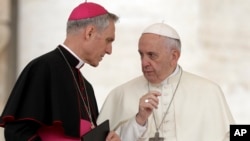 FILE - Pope Francis shares a word with Prefect of the Papal Household Georg Ganswein (L) during his weekly general audience, in St. Peter's Square, at the Vatican, May 2, 2018.