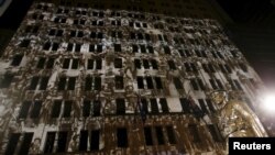 Old photographs of Australian soldiers are projected onto an office building alongside a bronze statue at the Cenotaph war memorial on ANZAC (Australian and New Zealand Army Corps) day in Sydney, April 25, 2015.
