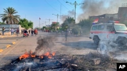 Protesters set fire to close a street in Sadr City during the ongoing anti-government protests in Baghdad, Iraq, Monday, Nov. 4, 2019. (AP Photo/Ali Abdul Hassan)