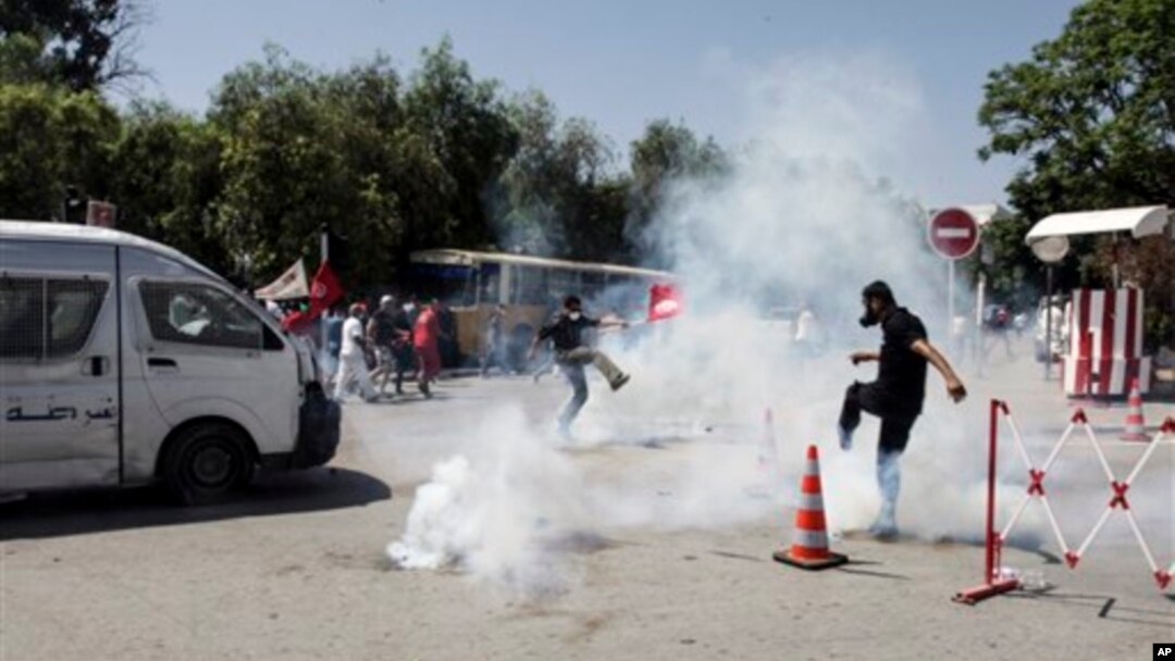Pendukung tokoh oposisi Tunisia Mohammed Brahmi berupaya melarikan diri dari gas air mata yang ditembakkan polisi, saat berlangsungnya bentrokan pasca pemakaman tokoh oposisi tersebut di Tunis (27/7).