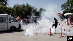 Pendukung tokoh oposisi Tunisia Mohammed Brahmi berupaya melarikan diri dari gas air mata yang ditembakkan polisi, saat berlangsungnya bentrokan pasca pemakaman tokoh oposisi tersebut di Tunis (27/7).