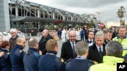 Le Premier ministre belge Charles Michel, au centre, serre la main des policiers et des premiers secours en face du terminal de l'aéroport endommagé Zaventem à Bruxelles le 23 Mars 2016. (AP Photo/Frederic Sierakowski)