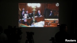 Journalists watch prosecutors and court officials on a live feed of the trial of Yuri Chaplinsky, Budapest, March 11, 2020.