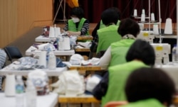 FILE - Volunteers make protective masks to protect against the coronavirus to donate to the neighbors in Seoul, South Korea, March 18, 2020.