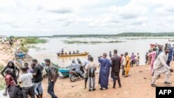 FILE - Passengers gather near informal motorised canoes ready to ferry passengers across the River Niger that divides Benin and Niger in the town of Malanville on September 18, 2023. Prices for the 30-minute journey have jumped tenfold on high demand, operators said.