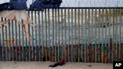 ຜູ້​ຊາຍ​ຄົນ​ນຶ່ງ ນອນ​ຢູ່​ທາງ​ຂ້າງ ກຳ​ແພງ​ເຂດ​ຊາຍ​ແດນ ສະ​ຫະ​ລັດ, ເມືອງ ທິ​ຮ​ວາ​ນາ, ເມັກ​ຊິ​ໂກ. 9 ມິ​ຖຸ​ນາ, 2019. (AP Photo/Eduardo Verdugo)