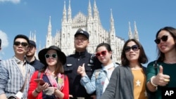 FILE - Chinese Police officer poses with Chinese tourists in Milan's Duomo square in Rome, Italy, May 3, 2016. 