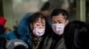 People traveling for the Lunar New Year wear protective masks as they head to the departure area at the Beijing Capital International Airport in Beijing on Jan. 22, 2020.