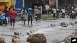 People wade past floodwaters after heavy rainfall in Hyderabad, in the Indian state of Telangana, where record rains and heavy flooding collapsed houses and killed more than a dozen people, Oct. 14, 2020. 