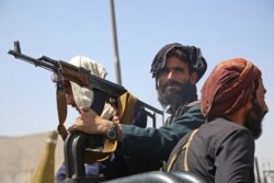 Taliban fighters stand guard in a vehicle along the roadside in Kabul on Aug. 16, 2021.