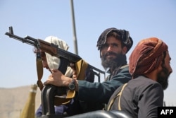 Taliban fighters stand guard in a vehicle along the roadside in Kabul on August 16, 2021.