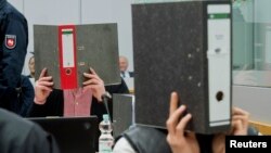 FILE - Defendants hide their faces as they wait for the start of their trial in a courtroom in Calle, Germany, Nov. 30, 2015. The suspected former Islamic State (IS) fighters are accused of being members of a terrorist group.