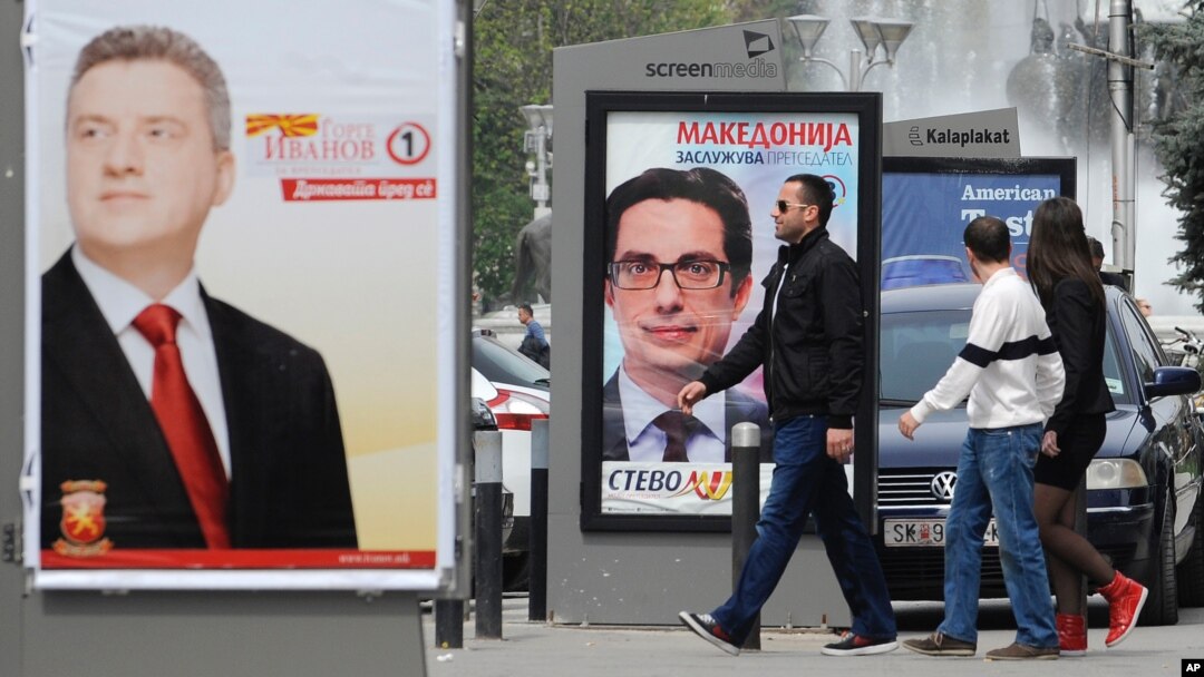 Young people pass beside boards with election posters of Gjorge Ivanov, (l), current Macedonian President and a candidate of the ruling conservative VMRO-DPMNE party, with a slogan "The State Before All", and Stevo Pendarovski, (c), a candidate of opposition Social-democrats, with a slogan "Macedonia Deserves a President", in Skopje, Macedonia. 