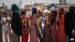 FILE - Women and children stand in line for food at Dibaga camp for internally displaced civilians, in Irbil province, Iraq, Aug. 7, 2016.