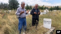 Adem Karaagac, left, and Satilmis Karatekin pray at the grave of a distant relative of Boris Johnson, in Kalfat, a village in the Cankiri province, 100 kilometers (62 miles) north of the Turkish capital Ankara, Turkey, July 25, 2019.