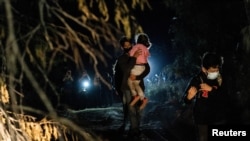 Asylum-seeking migrant families walk to turn themselves in to the U.S. Border Patrol after crossing the Rio Grande river into the United States from Mexico in Roma, Texas, April 27, 2021. (REUTERS/Go Nakamura)