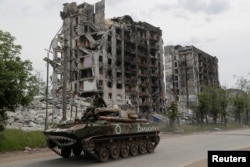 Service members of pro-Russian troops drive an armoured vehicle in Popasna