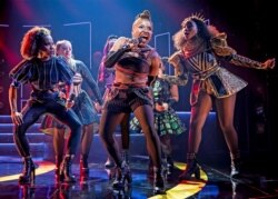 This image released by Boneau/Bryan Brown shows Brittney Mack, center, during a performance of "Six." Samantha Pauly and Mack, who play two wives of Henry VIII in the musical “Six,” have turned their disappointment at having their musical on hold.
